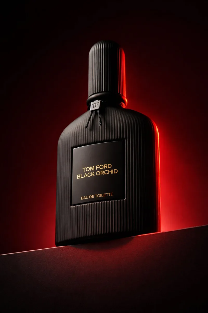 Black ribbed perfume bottle on a dark plinth with a red edge light